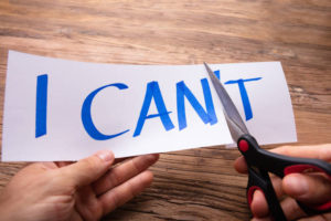 Person's Hand Cutting Paper Word I Can't With Scissor Over Wooden Background